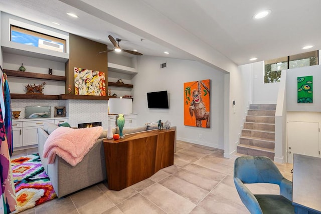 tiled living room featuring ceiling fan, a fireplace, and vaulted ceiling