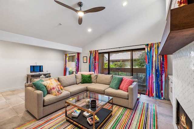 tiled living room featuring a stone fireplace, ceiling fan, and vaulted ceiling