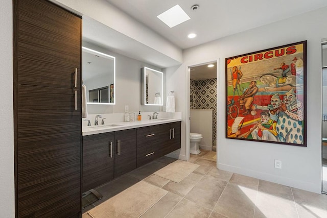 bathroom with tile patterned floors, vanity, a skylight, and toilet