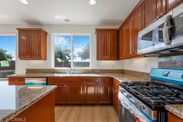 kitchen featuring sink, light stone counters, light wood-type flooring, and stainless steel appliances