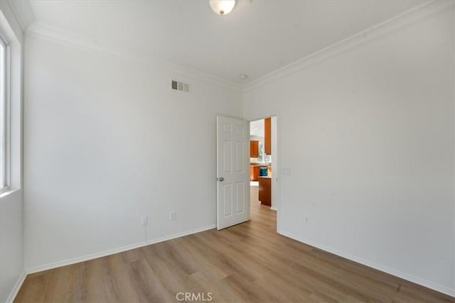 unfurnished room featuring ornamental molding and light wood-type flooring