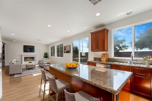 kitchen featuring light stone countertops, sink, light hardwood / wood-style flooring, dishwasher, and a center island