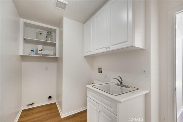 laundry room featuring cabinets, hookup for a washing machine, hardwood / wood-style flooring, and sink