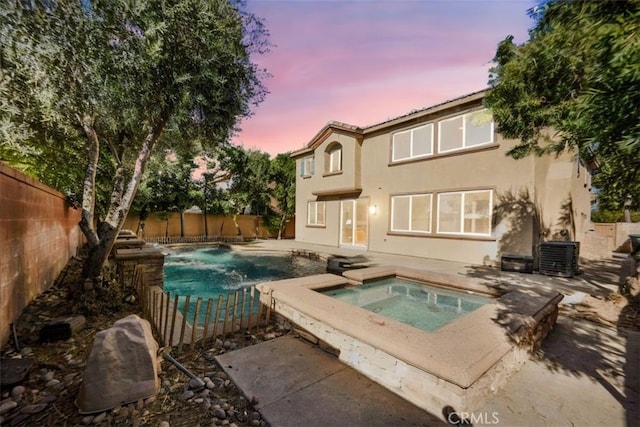 back house at dusk with a swimming pool with hot tub and cooling unit