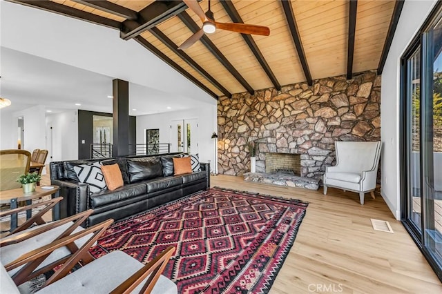 living room featuring lofted ceiling with beams, a stone fireplace, wooden ceiling, and light hardwood / wood-style flooring