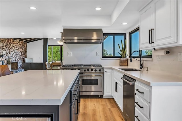 kitchen featuring sink, stainless steel appliances, a fireplace, white cabinets, and exhaust hood