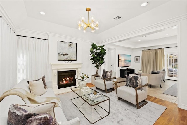 living room with a tray ceiling, light hardwood / wood-style flooring, and a notable chandelier