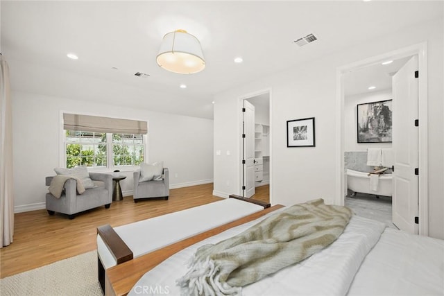 bedroom featuring ensuite bath, a spacious closet, and wood-type flooring