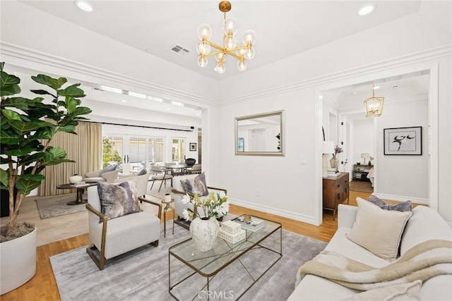 living room featuring a chandelier, hardwood / wood-style floors, and ornamental molding