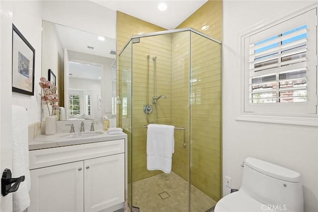 bathroom with an enclosed shower, vanity, toilet, and a wealth of natural light