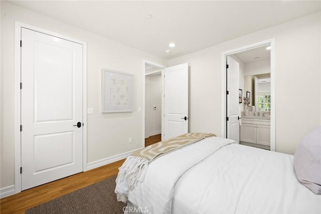 bedroom with connected bathroom, sink, and wood-type flooring