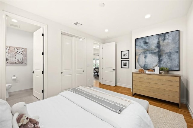 bedroom featuring ensuite bathroom, a closet, and wood-type flooring