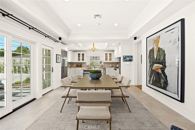 dining space featuring sink, a raised ceiling, a notable chandelier, light tile patterned floors, and ornamental molding