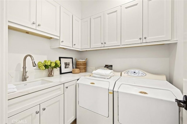 washroom with cabinets, washer and dryer, and sink