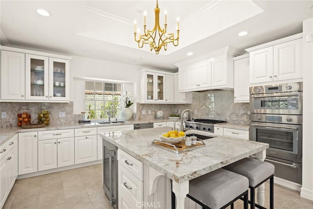 kitchen featuring backsplash, white cabinetry, sink, and a kitchen island with sink