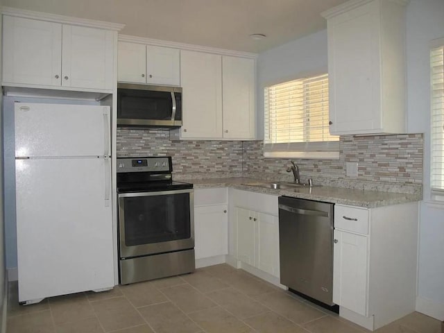 kitchen featuring white cabinetry, stainless steel appliances, light tile patterned floors, and tasteful backsplash