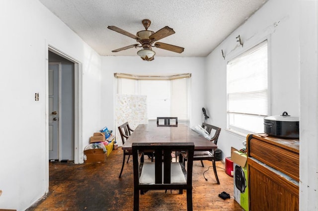 dining area featuring ceiling fan and a textured ceiling