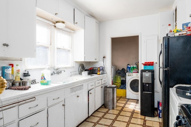 kitchen featuring white cabinetry, black fridge, stove, washer / clothes dryer, and sink