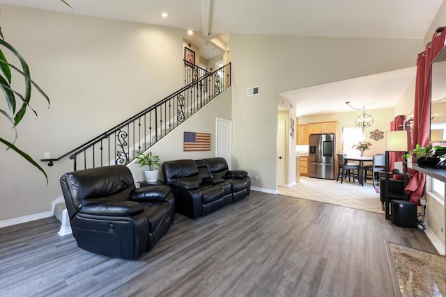 living room featuring an inviting chandelier, high vaulted ceiling, a healthy amount of sunlight, and hardwood / wood-style flooring