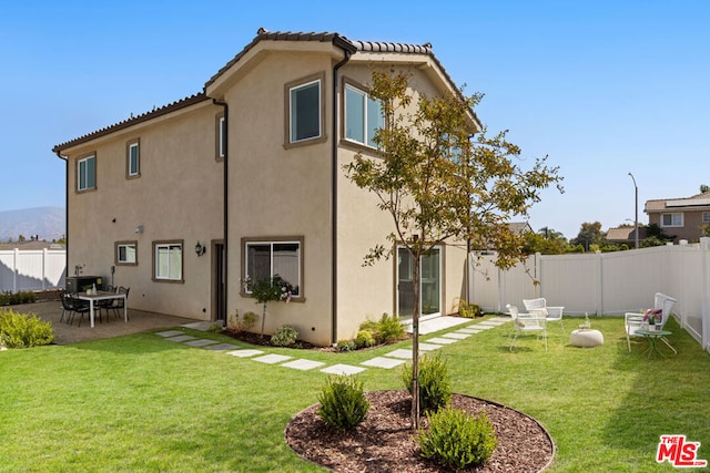 back of house with a lawn and a patio