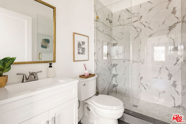 bathroom featuring a tile shower, vanity, and toilet