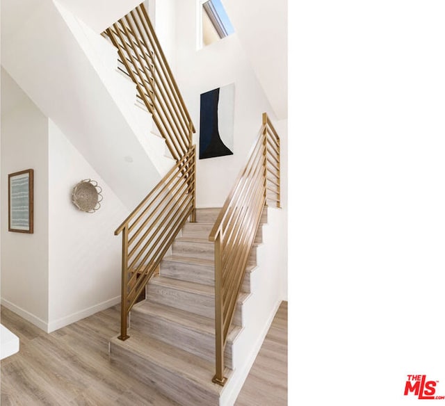 stairs featuring a high ceiling and hardwood / wood-style flooring