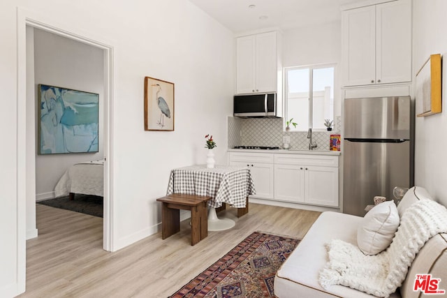 kitchen featuring white cabinets, appliances with stainless steel finishes, and light hardwood / wood-style flooring