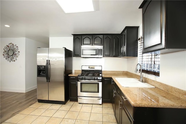 kitchen featuring light stone counters, sink, light tile patterned floors, and appliances with stainless steel finishes