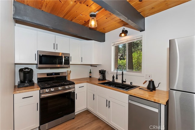 kitchen featuring white cabinetry, butcher block counters, appliances with stainless steel finishes, and sink