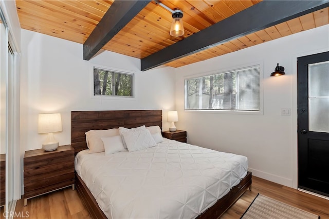 bedroom featuring wood-type flooring, beam ceiling, and multiple windows