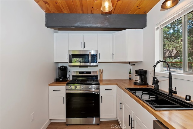 kitchen featuring appliances with stainless steel finishes, wood counters, sink, and white cabinets