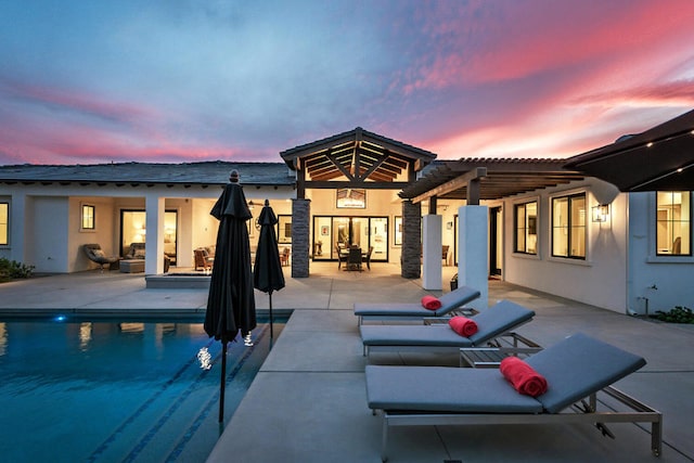 pool at dusk with a pergola and a patio area