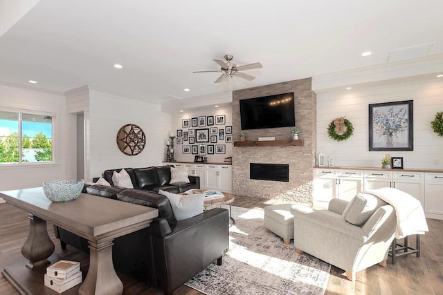 living room with wood-type flooring, ceiling fan, and a stone fireplace