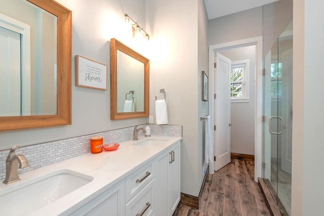 bathroom with backsplash, vanity, a shower with shower door, and hardwood / wood-style flooring