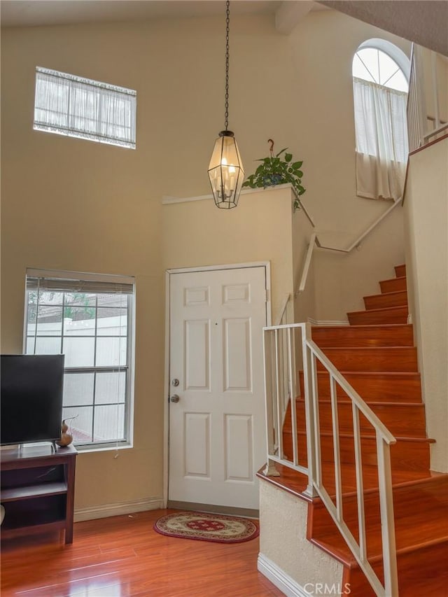 foyer entrance with high vaulted ceiling and hardwood / wood-style flooring