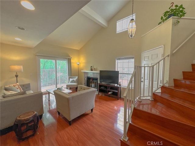 living room with a fireplace, wood-type flooring, high vaulted ceiling, and beamed ceiling