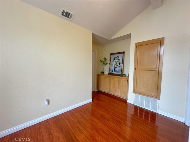 spare room featuring hardwood / wood-style floors and vaulted ceiling