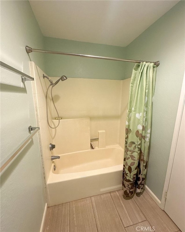 bathroom with hardwood / wood-style flooring and shower / bathtub combination with curtain