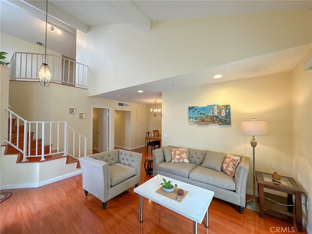 living room with a chandelier, beam ceiling, hardwood / wood-style flooring, and high vaulted ceiling