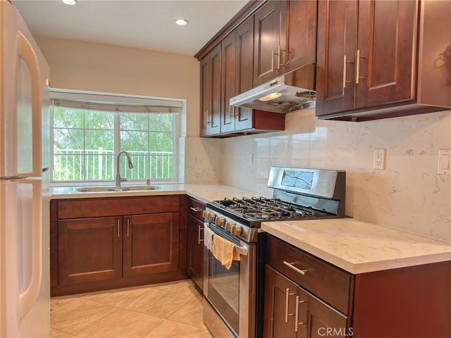 kitchen featuring stainless steel range with gas cooktop, sink, light tile patterned floors, tasteful backsplash, and white fridge