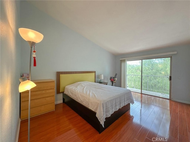 bedroom with hardwood / wood-style floors, access to exterior, and vaulted ceiling