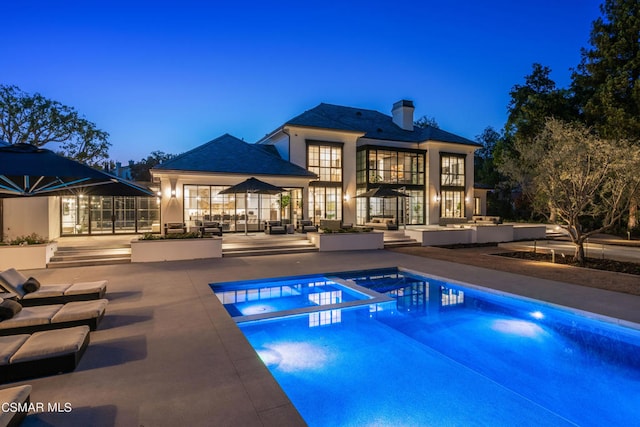 pool at dusk with a patio and french doors