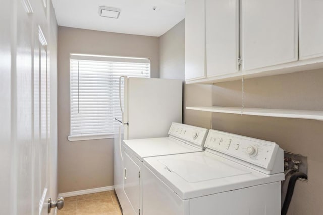 laundry area with cabinets, light tile patterned floors, and washer and clothes dryer