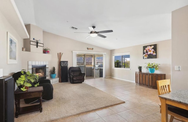 tiled living room featuring ceiling fan, a fireplace, and vaulted ceiling