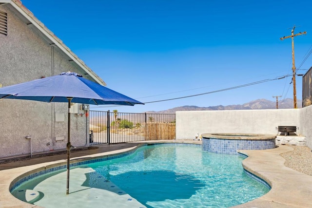 view of pool with a mountain view and an in ground hot tub