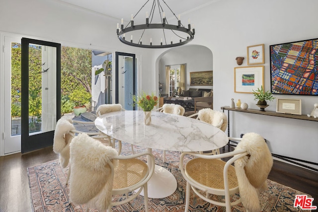 dining space featuring dark hardwood / wood-style flooring, crown molding, and an inviting chandelier