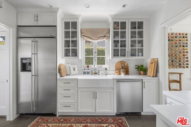 kitchen featuring white cabinets, dark tile patterned floors, sink, and appliances with stainless steel finishes