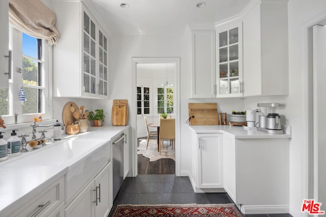 kitchen featuring stainless steel dishwasher, sink, white cabinetry, and dark wood-type flooring