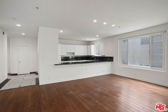 kitchen featuring white cabinets, kitchen peninsula, sink, and light hardwood / wood-style flooring