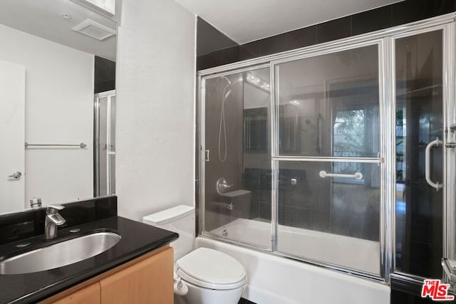 full bathroom featuring vanity, enclosed tub / shower combo, and toilet